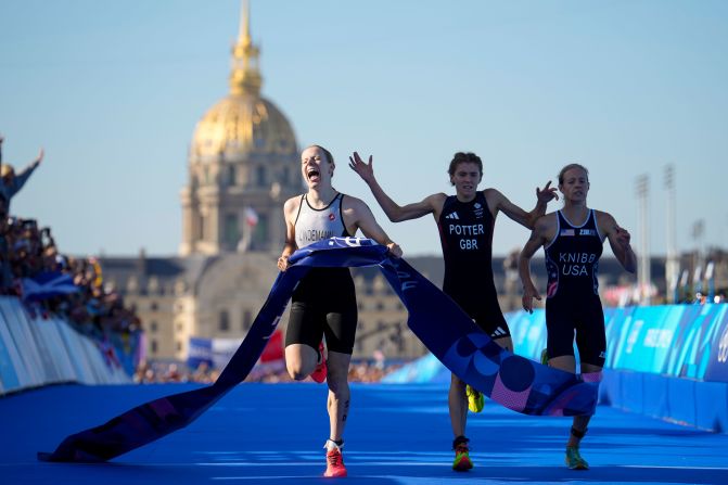 Triathlete Laura Lindemann, left, celebrates after she crossed the finish line <a href=