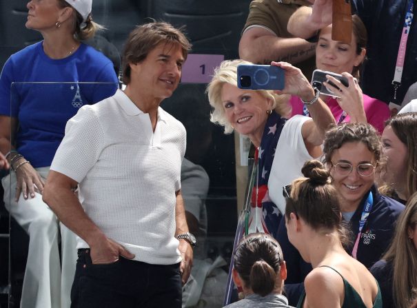 Actor Tom Cruise takes a photo with a fan during the women's gymnastics qualification round on July 28. <a href=