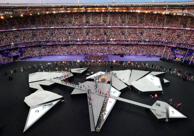 Flagbearers from every country enter the Stade de France and walk onto the stage at the start of the closing ceremony.