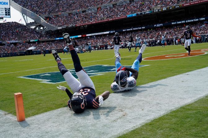 Tennessee Titans tight end Chigoziem Okonkwo, right, and Chicago Bears cornerback Tyrique Stevenson tumble in the end zone in Chicago on September 8. Okonkwo made the catch for a touchdown, but the Titans ultimately fell 24-17 to the Bears.