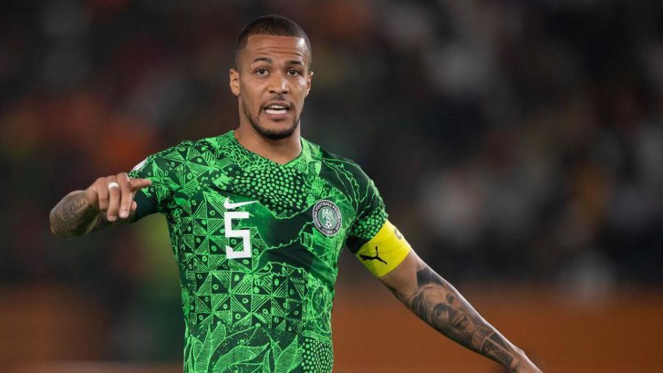 William Troost-Ekong, wearing a green Nigeria shirt, points with his right hand while playing at the 2023 Africa Cup of Nations