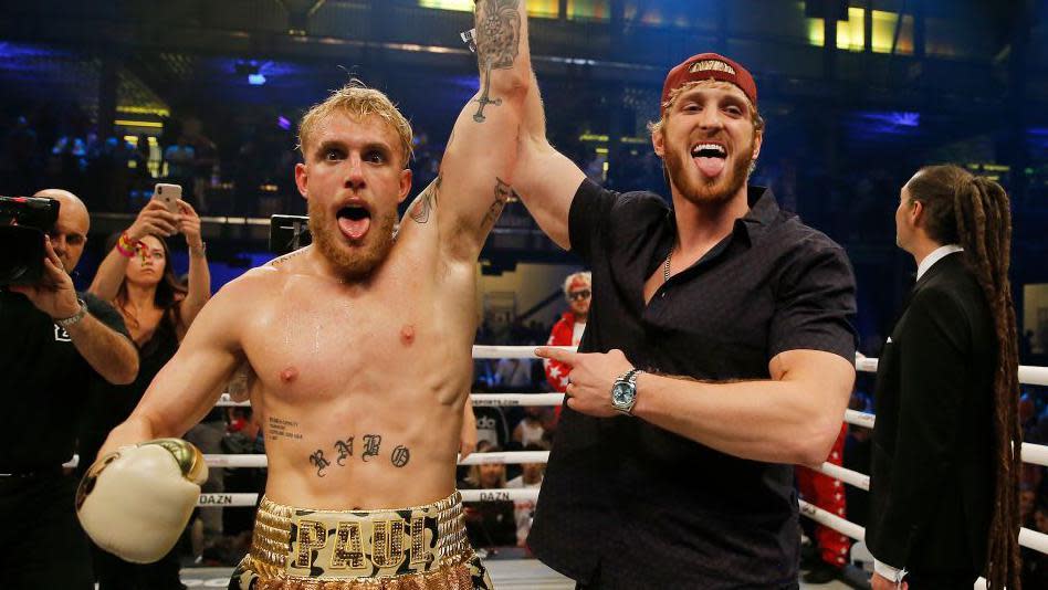 Logan Paul (right) raises the arm of his brother Jake Paul in the ring